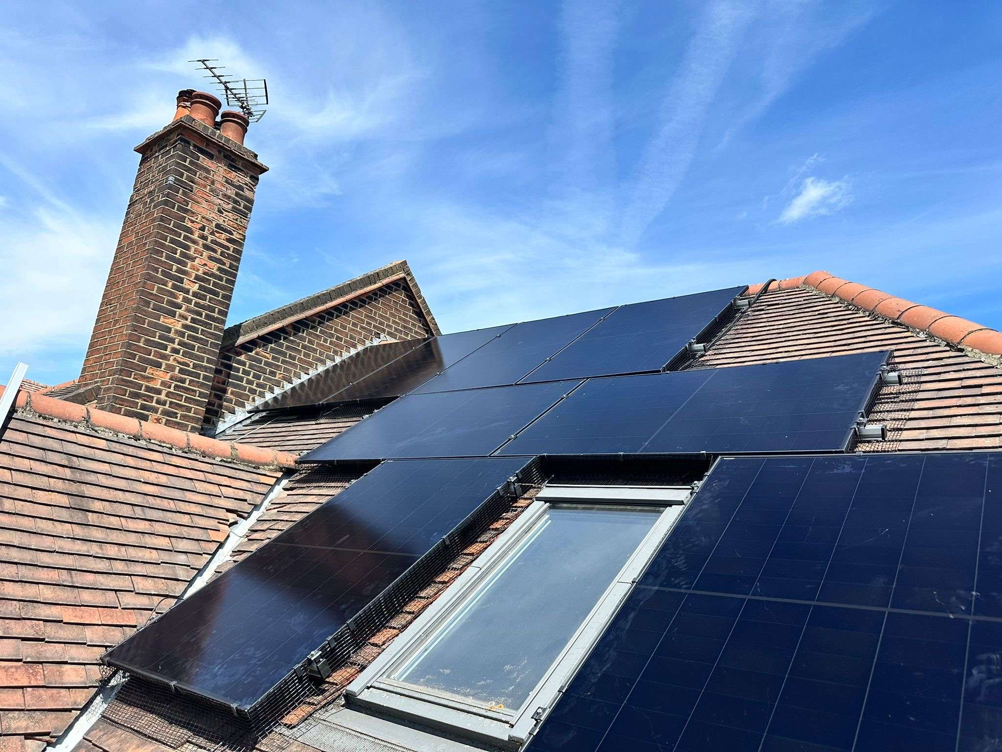 Black solar panels arranged around a roof window